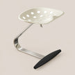 A modern ergonomic office chair with a white perforated seat, a curved chrome metal base, and a black footrest, shown on a solid beige background.