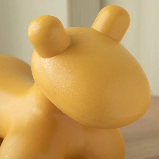 Yellow teddy bear-shaped object on a neutral background