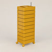 A modern mustard yellow rolling storage cabinet with eight stacked drawers and a metal rod on top, set against a plain light gray background.