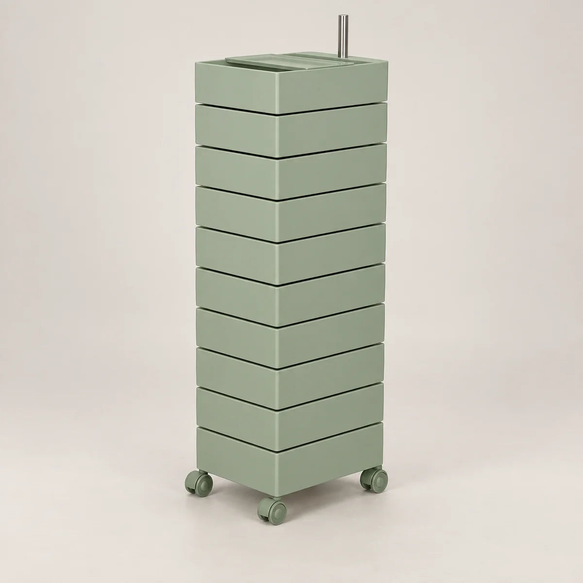 A tall, narrow rolling storage cart with multiple stacked drawers in a muted sage green color, featuring a metal handle on top and small caster wheels at the base, shown against a plain light gray studio background.