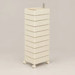 A tall, cream-colored rolling storage cabinet with multiple stacked drawers and a metal handle on top, set against a solid light gray background.