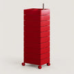 A tall red storage cart with multiple stacked drawers and small wheels, shown on a clean light gray studio background.