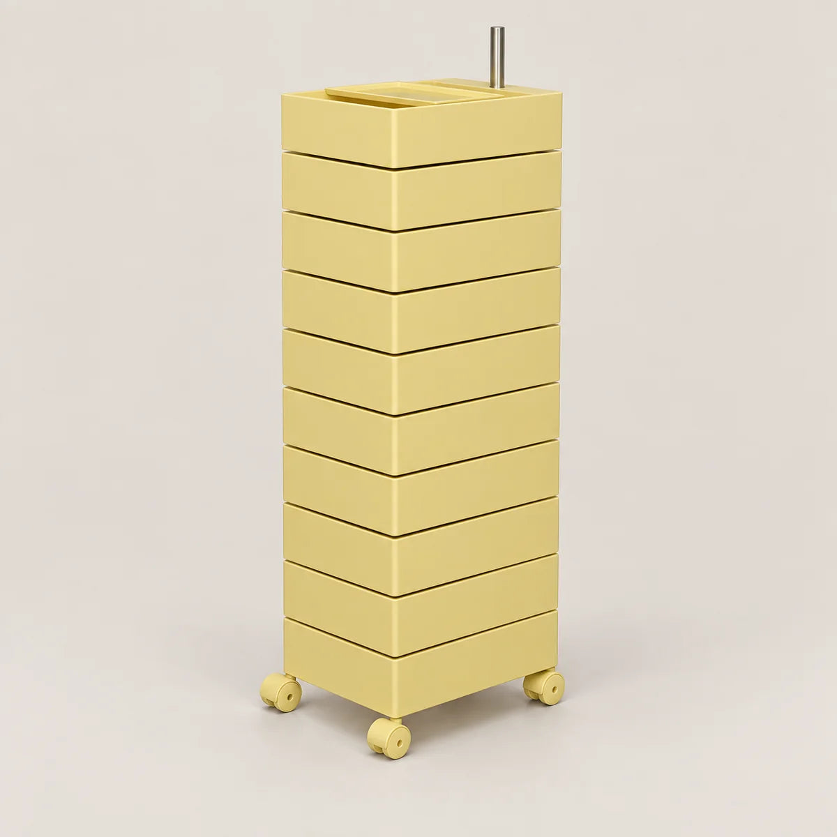 A tall, minimalist rolling storage unit with ten stacked drawers in a pale yellow color, featuring a top tray and four caster wheels, set against a solid light beige background.