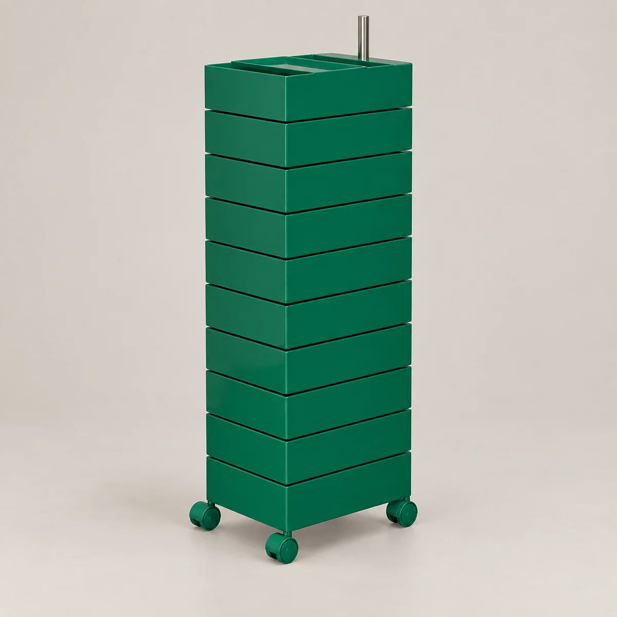 A tall, green rolling storage cabinet with multiple stacked drawers or compartments, a rectangular top, and small wheels on the base, photographed against a plain light beige studio background.