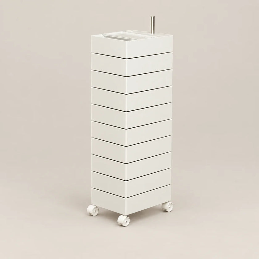 A tall, narrow white rolling storage cabinet with multiple drawers and a small metal handle on top, shown on a plain warm beige studio background.
