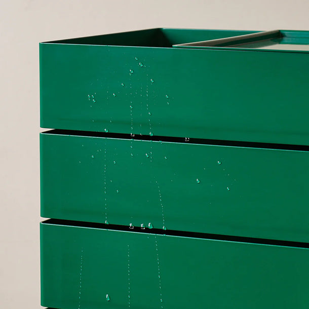 Green metal planter box on a beige background