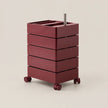 A dark red rolling storage cart with five stacked drawers and a metal handle, shown on a light beige background.