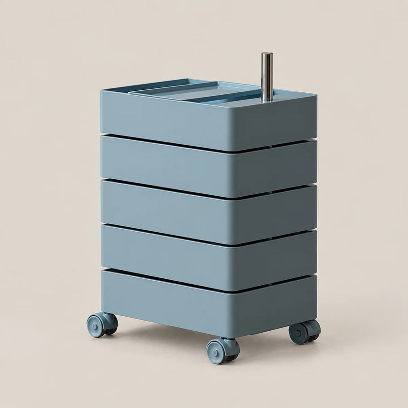 A modern four-drawer rolling storage cart in a muted dusty blue-gray color, featuring a silver metal handle on top and four caster wheels, set against a solid light beige background.