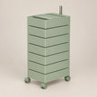 A mint green rolling storage cabinet with six stacked drawers and a metal handle on top, set against a solid beige background.