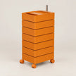 An orange rolling storage cart with six stacked drawers and a metal handle on top, photographed on a clean light gray studio background.