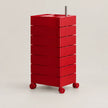 A red rolling storage cart with eight stacked drawers and a metal handle, photographed on a clean light gray studio background.