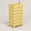 A pastel yellow rolling storage cart with six stacked drawers and a metal handle on top, shown on a light gray studio background.