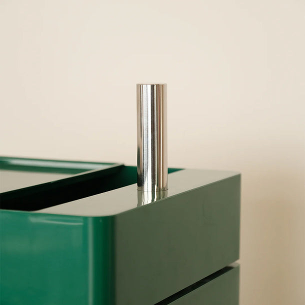 Green glass cabinet with a metallic handle on a beige background