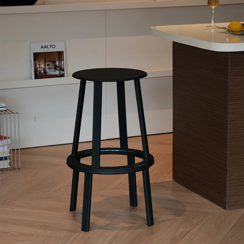 Black bar stool in a modern kitchen setting with a white countertop and wooden floor.
