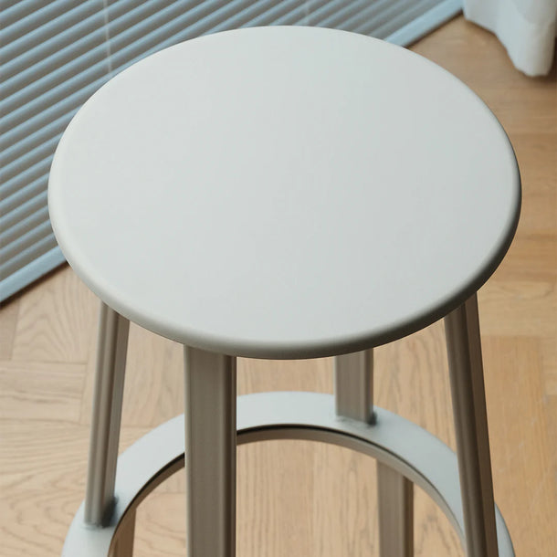 Round stool with a light gray seat and legs on a wooden floor.