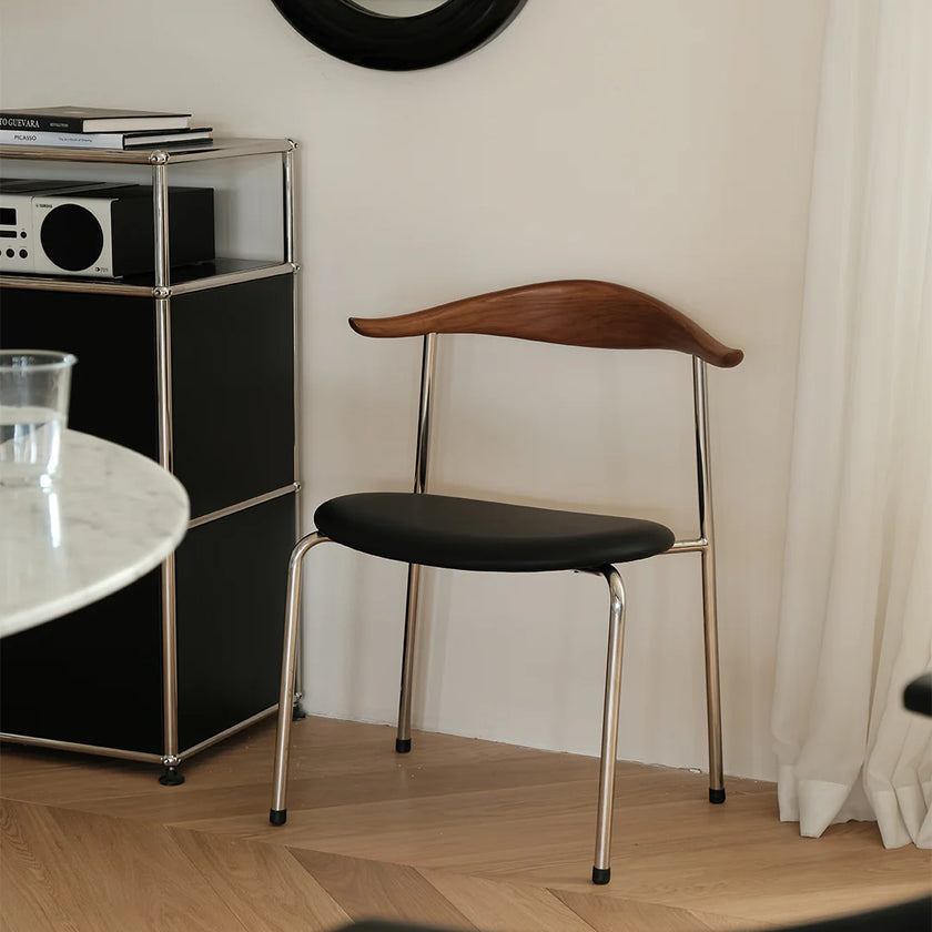 Modern chair with wooden backrest and black seat in a room setting.