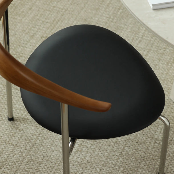 Black chair seat with wooden armrest on a carpeted floor