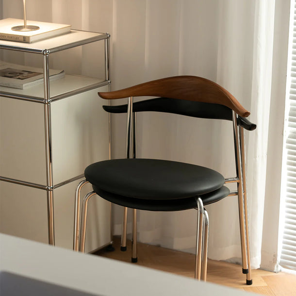 Modern chair with black seat and wooden backrest in a room with a shelf and window.
