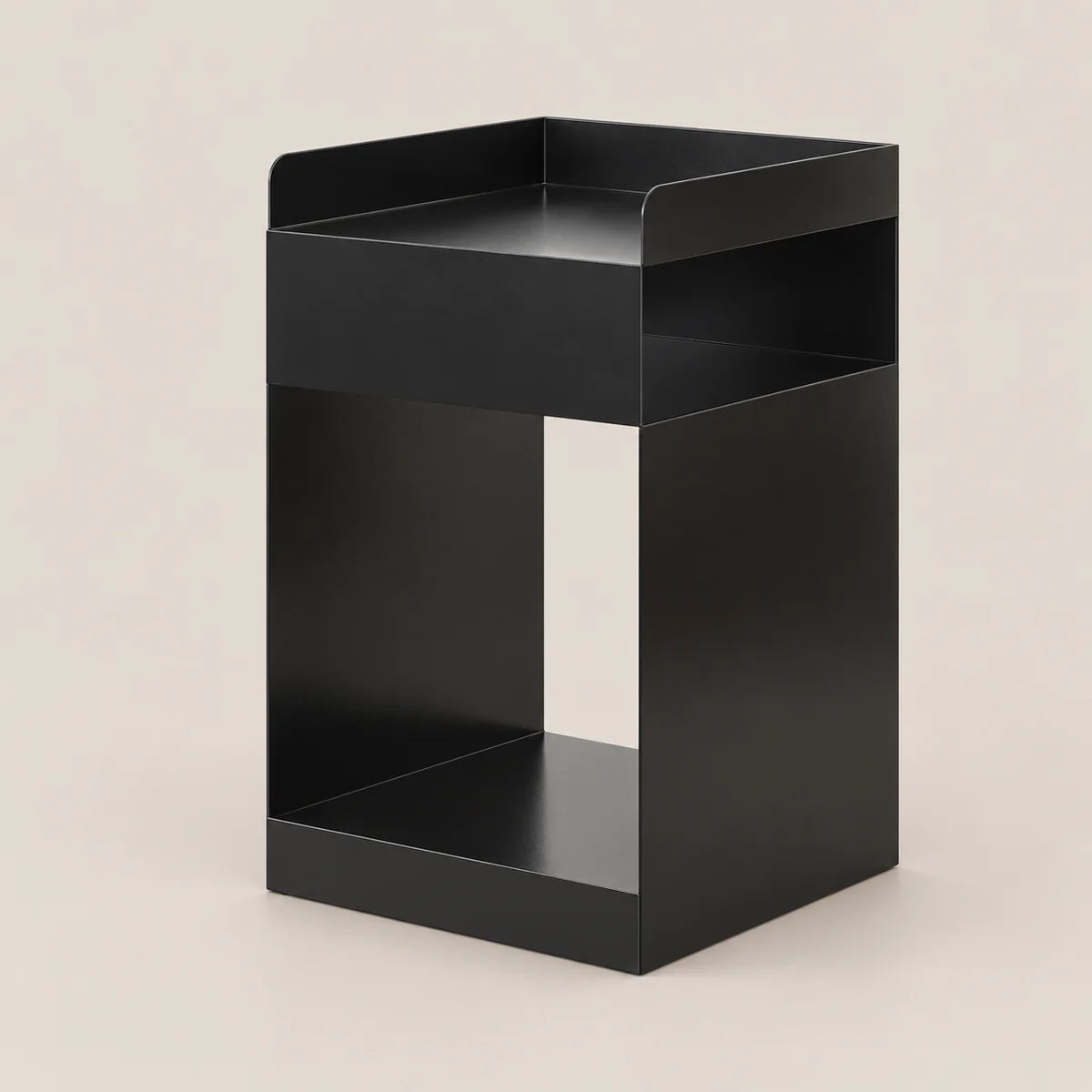 A minimalist black metal side table with a rectangular top tray, two open shelves, and a lower base, shown on a solid light beige background.