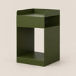 An olive green metal side table with a minimalist open design, featuring a top tray, a central open shelf, and a bottom shelf, set against a solid light beige background.
