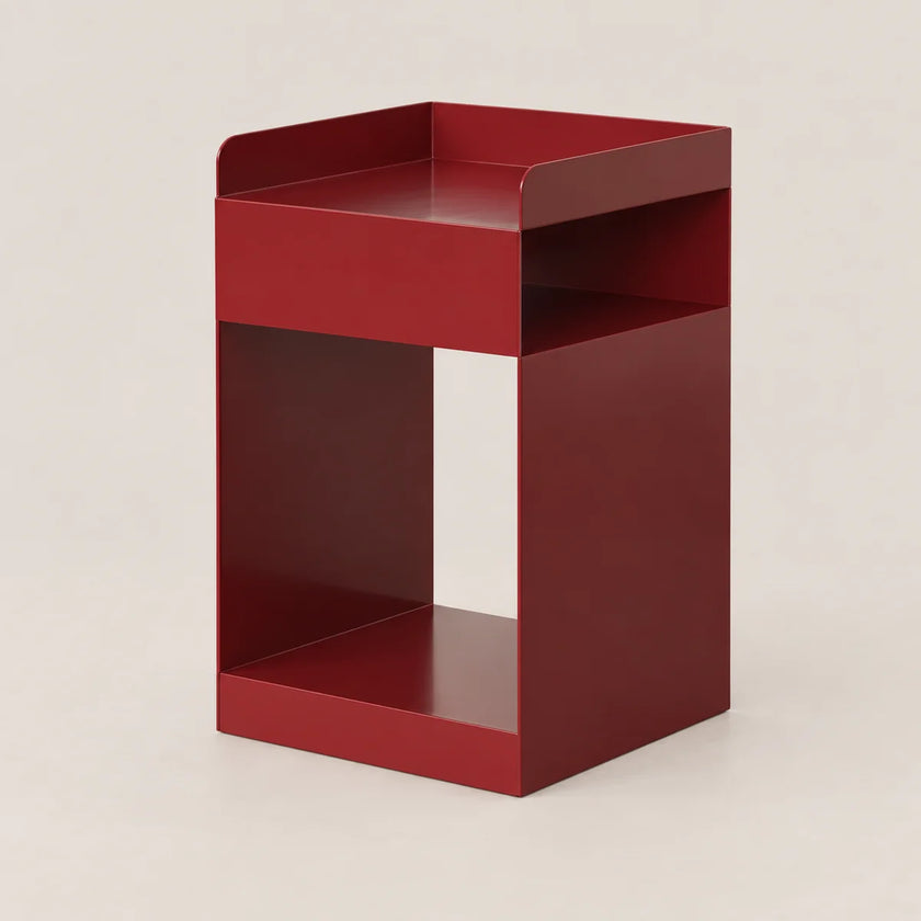 A modern, minimalist red metal side table with a geometric open design, photographed on a neutral light beige background.