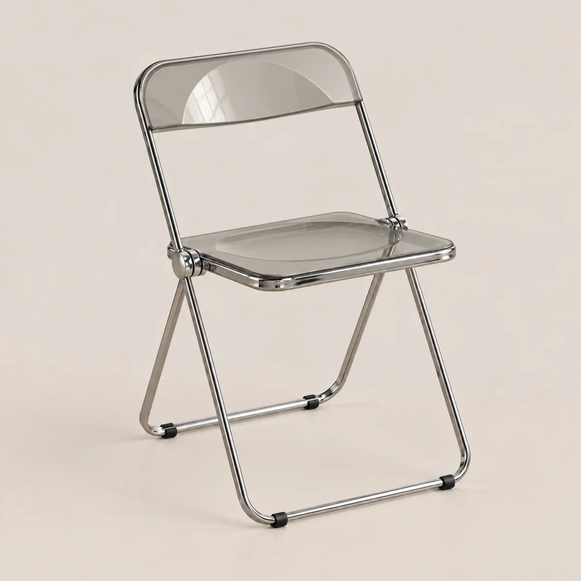 A modern folding chair with a transparent smoky-gray seat and backrest, supported by a polished silver metal frame, set against a solid light beige background.