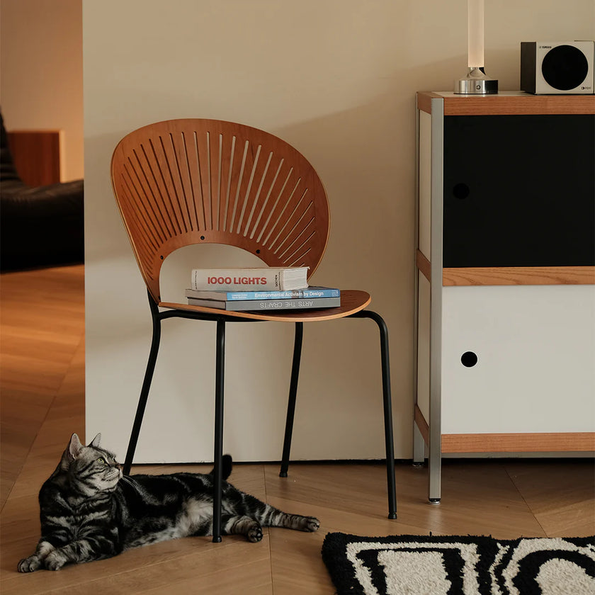 Wooden chair with books and a cat on a wooden floor next to a cabinet.
