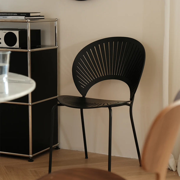 Black chair in a room with a shelf and books.