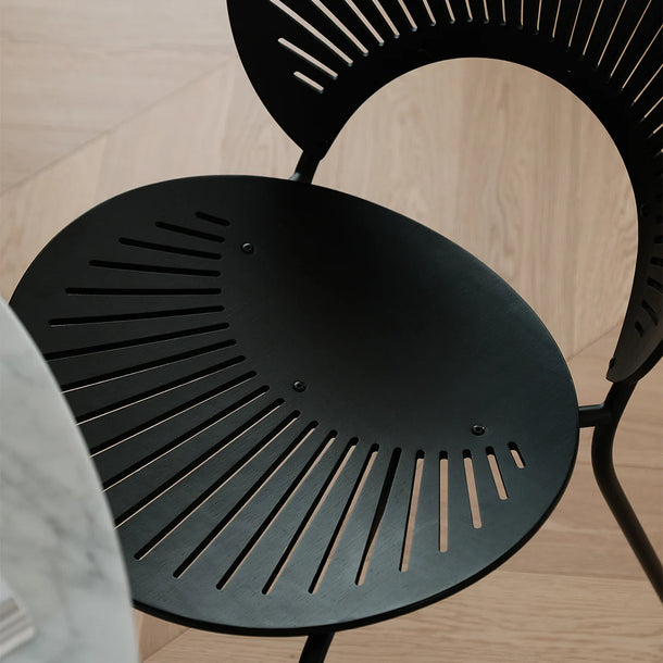 Black metal chair with a geometric design on a wooden floor