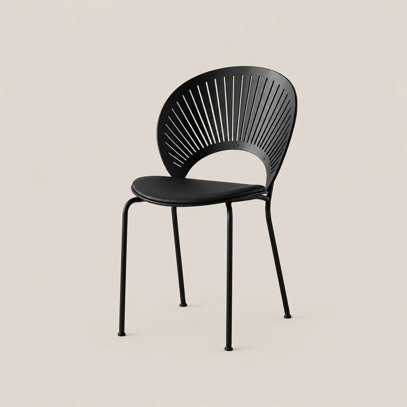 A modern black metal dining chair with a slatted oval backrest and four slim legs, shown against a solid light beige background.
