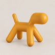 A mustard yellow dog-shaped stool with a matte finish, photographed on a clean, light beige background.