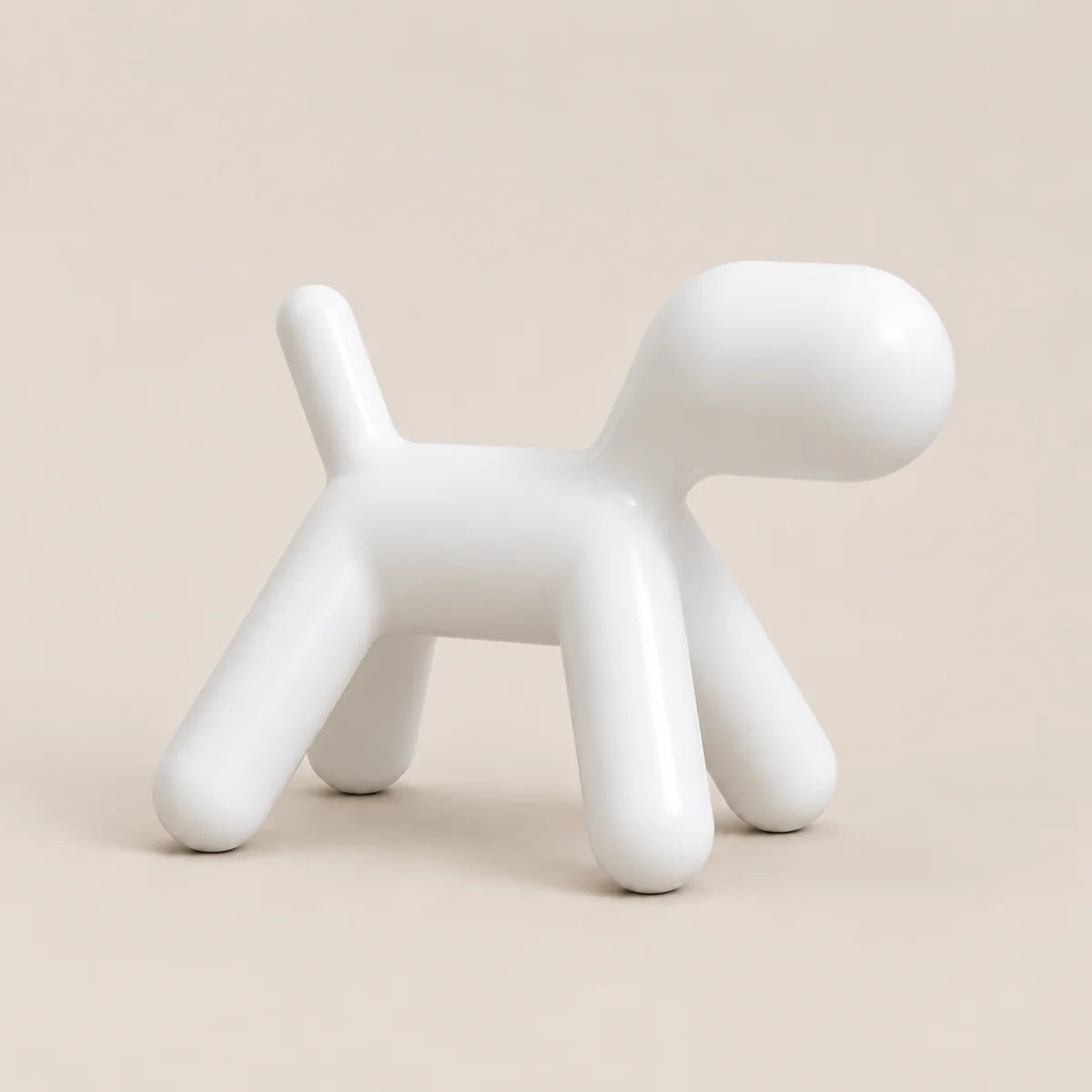 A minimalist white ceramic dog-shaped stool with a glossy finish, set against a solid beige background.