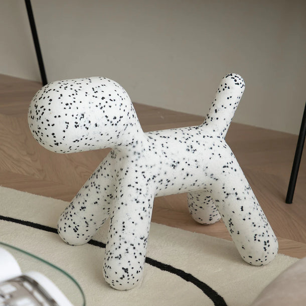 White dog-shaped stool with black speckles on a wooden floor.