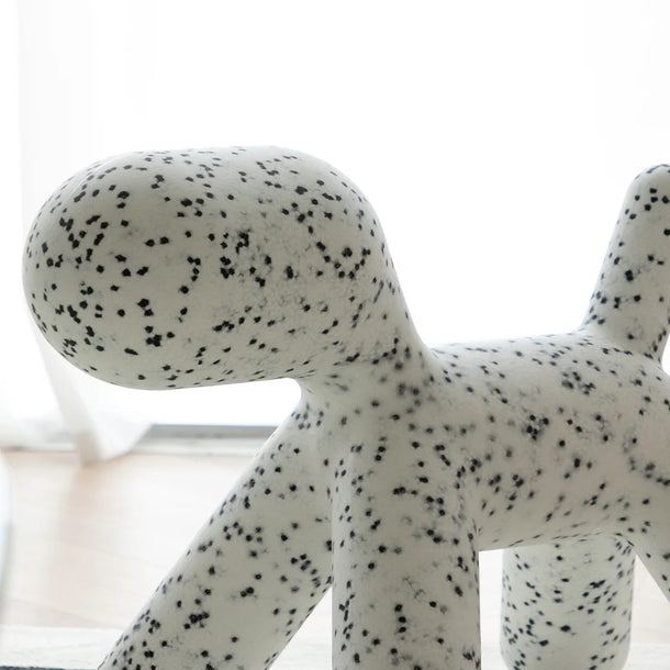 White dog-shaped object with black spots on a white background