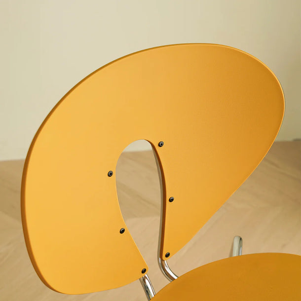 Close-up of a yellow chair with a curved design on a beige background