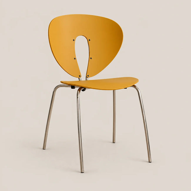 A modern side chair with a curved mustard yellow plastic shell and slim silver metal legs, shown against a solid light beige background.