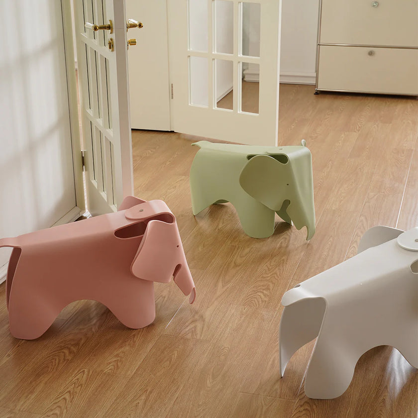 Three colorful elephant-shaped stools on a wooden floor.