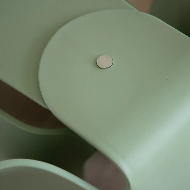 Close-up of a light green chair with a circular metallic button on a blurred background