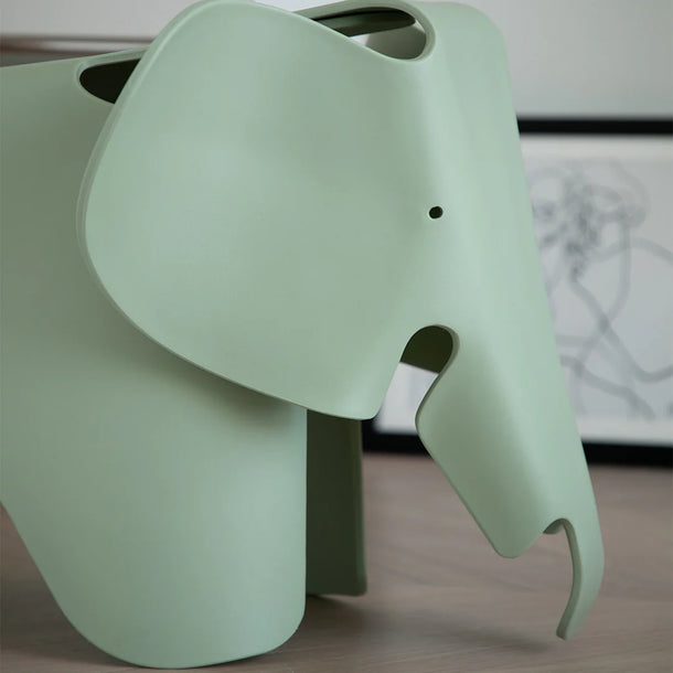 Green elephant-shaped object on a wooden surface with a blurred background