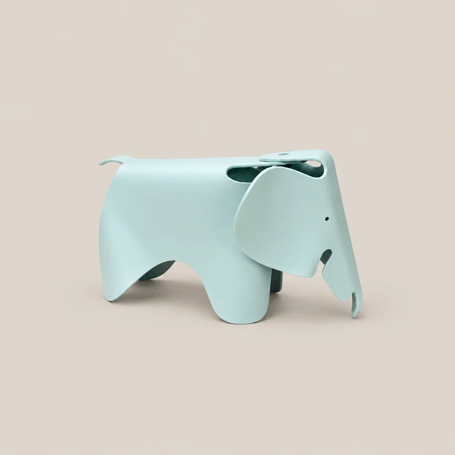 A light blue elephant-shaped stool with a matte finish, shown from the side against a solid beige background.