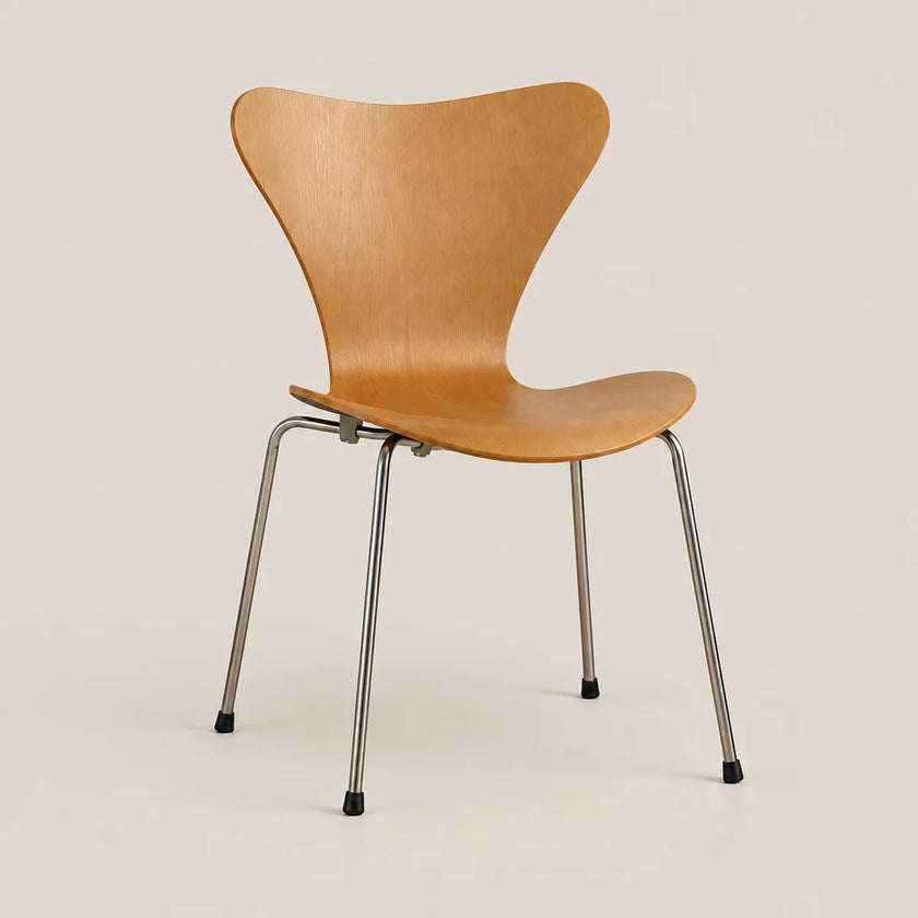 A mid-century modern wooden dining chair with a curved, shell-like backrest and seat in a warm light oak finish, supported by slim chrome metal legs with black rubber feet, set against a solid light beige background.