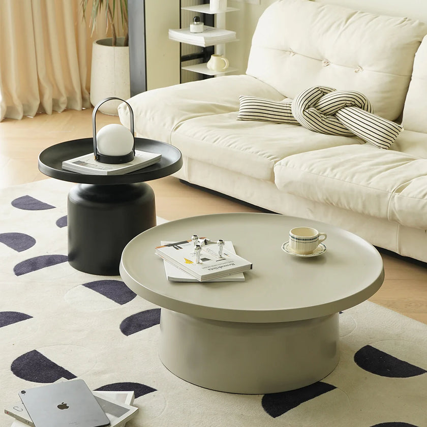 Round coffee table with a white sofa and decorative items in a living room setting.