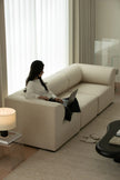 Woman using a laptop on a beige sectional sofa in a modern living room.