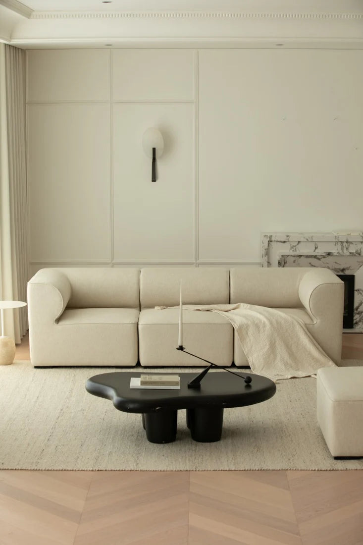 Modern living room with a beige sectional sofa and a black coffee table.
