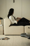 Person sitting on a beige sofa using a tablet in a modern living room.