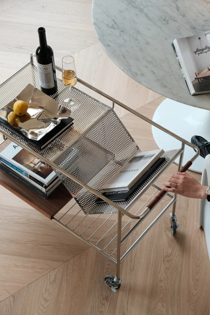 Metal serving cart with wine and snacks on a wooden floor