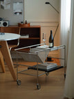 Metal serving cart with a bottle of wine and glasses in a room setting.