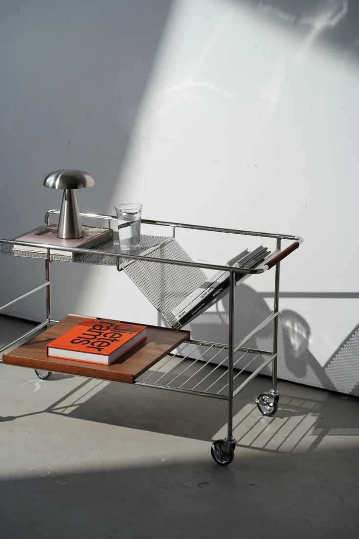 Modern bar cart with glass top and wooden shelf against a white wall.