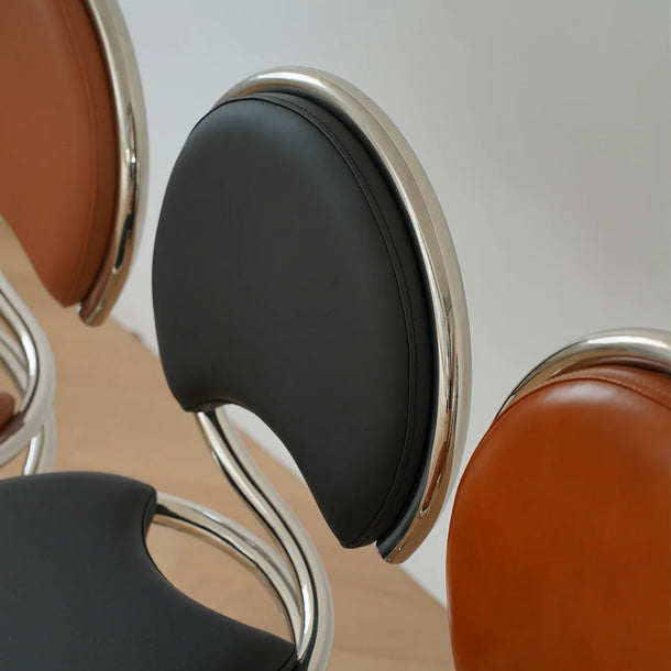 Close-up of a modern chair with black cushion and metallic frame.