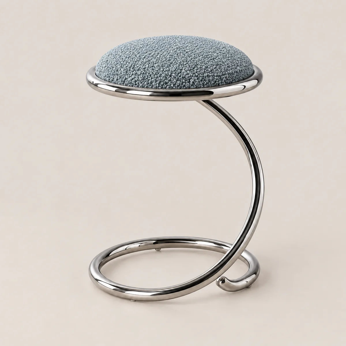 A modern stool with a textured light blue fabric cushion on a curved, polished chrome metal base, set against a solid beige background.
